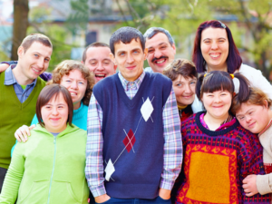 A large group of adults of different ages and different disabilities smiling at the camera.