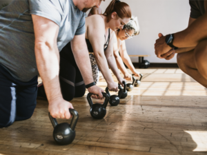 A group of people working out with kettle bells why a trainer watches