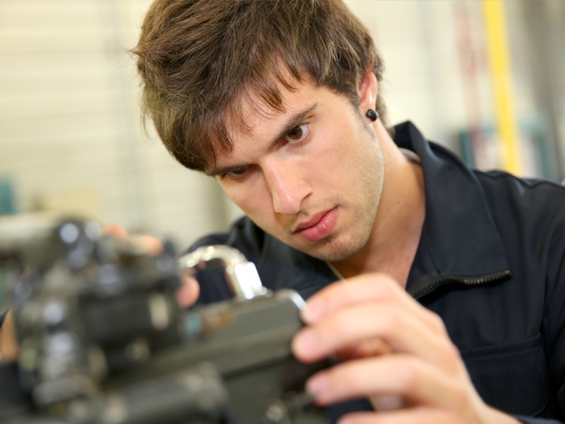 A young man working on auto parts with his hands.