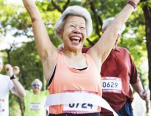 A older woman coming through a finish line after running a race.