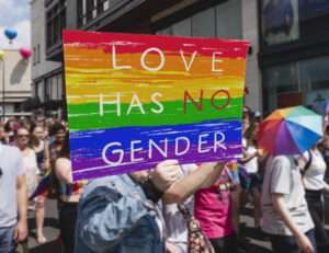 A person holding a sign in a parade or protest that reads Love has no gender